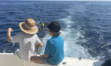 Niños en un barco de pesca en Mallorca, disfrutando del día soleado.