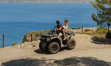 Pareja en quad parada frente al mar. contemplando el paisaje.