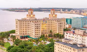 Fachada del Hotel Nacional de Cuba desde sus jardines, con banderas y arquitectura de estilo ecléctico.