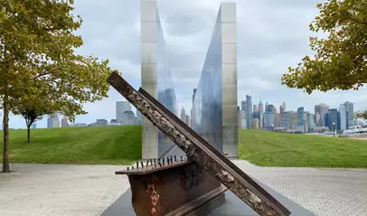 Monumento conmemorativo del 11S con vigas de acero y vista de Manhattan desde Liberty State Park.
