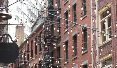 Calle Stone Street en Nueva York con luces colgantes y fachadas de ladrillo estilo histórico.