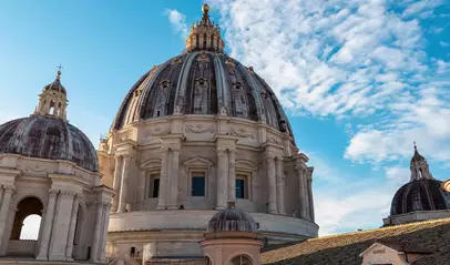 Vista exterior de la cúpula de la Basílica de San Pedro bajo un cielo azul, Ciudad del Vaticano.